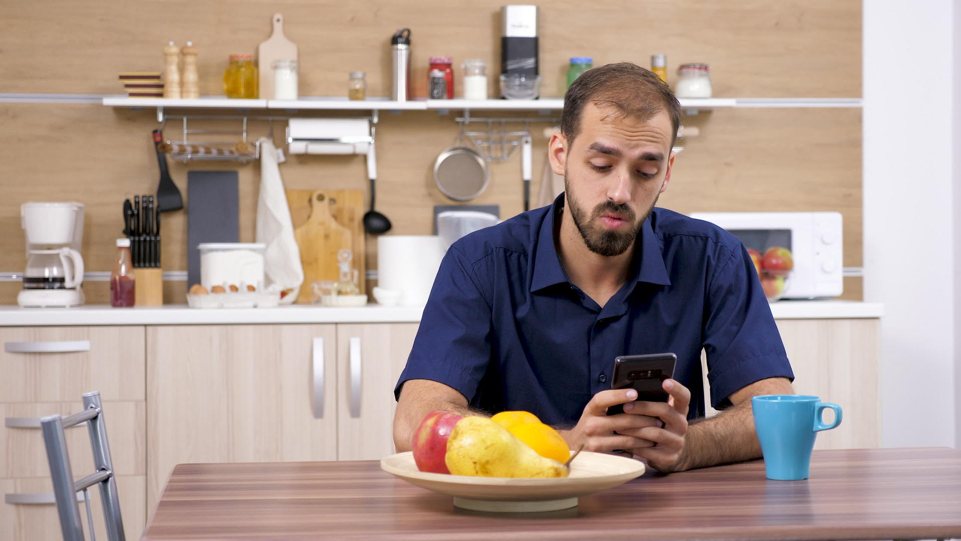 男人在厨房的桌子上用智能手机视频的预览图