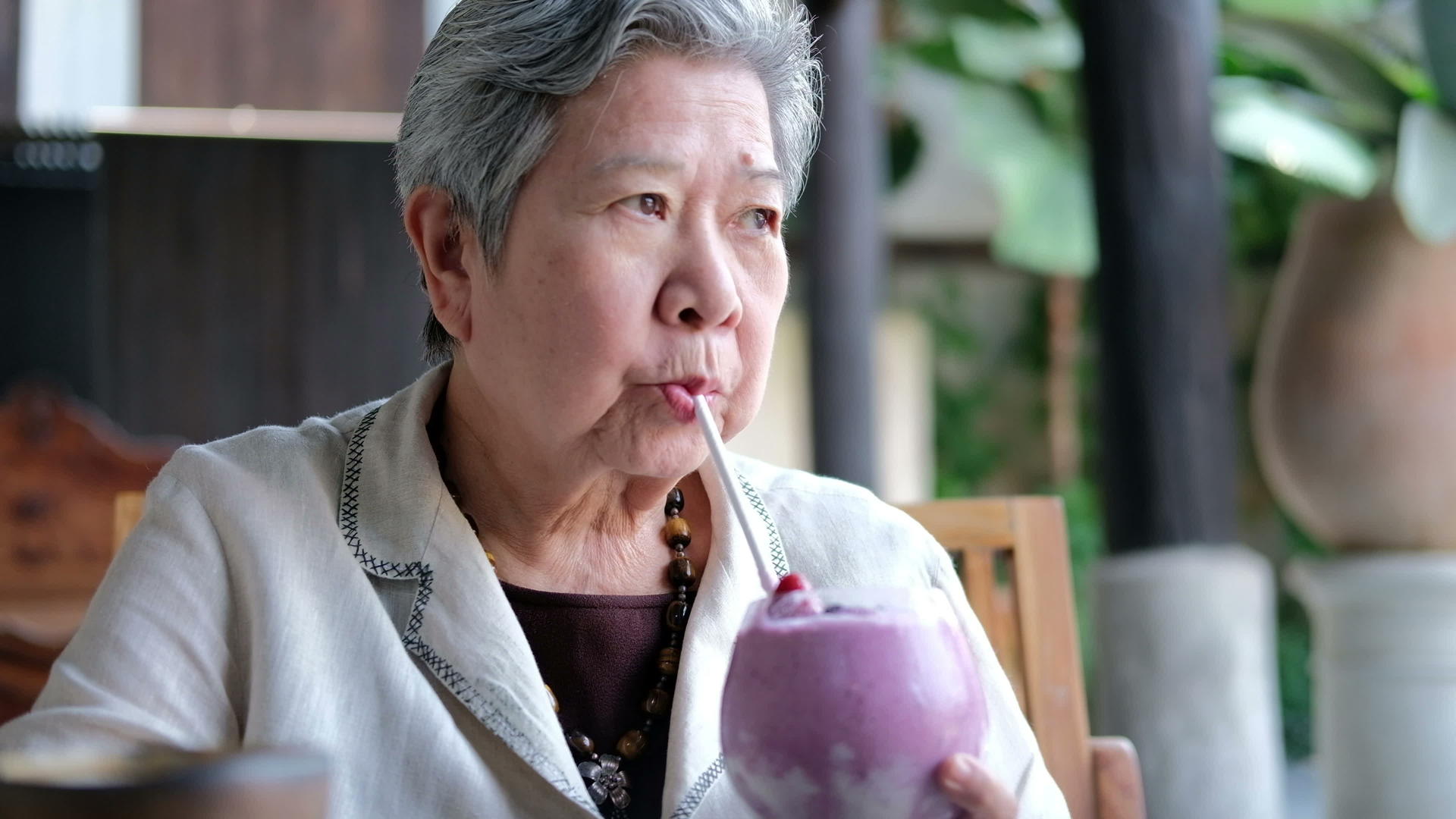 亚洲老年妇女在餐馆喝浆果冰沙奶昔视频的预览图