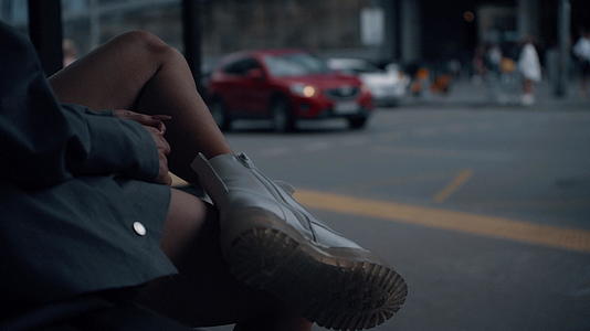 女性腿公共汽车站在城市背景下视频的预览图