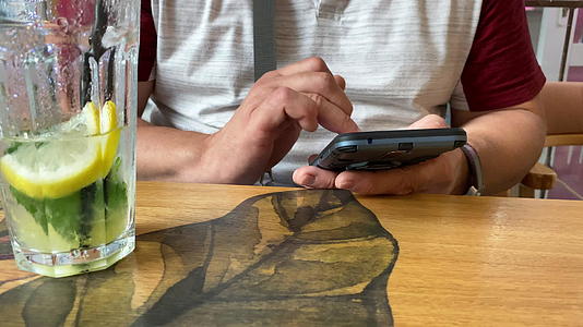成年男子坐在咖啡馆的桌子上用手指触摸智能手机屏幕视频的预览图