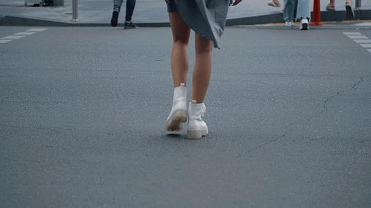 女孩双腿在市中心街道的人行横道上过马路视频的预览图