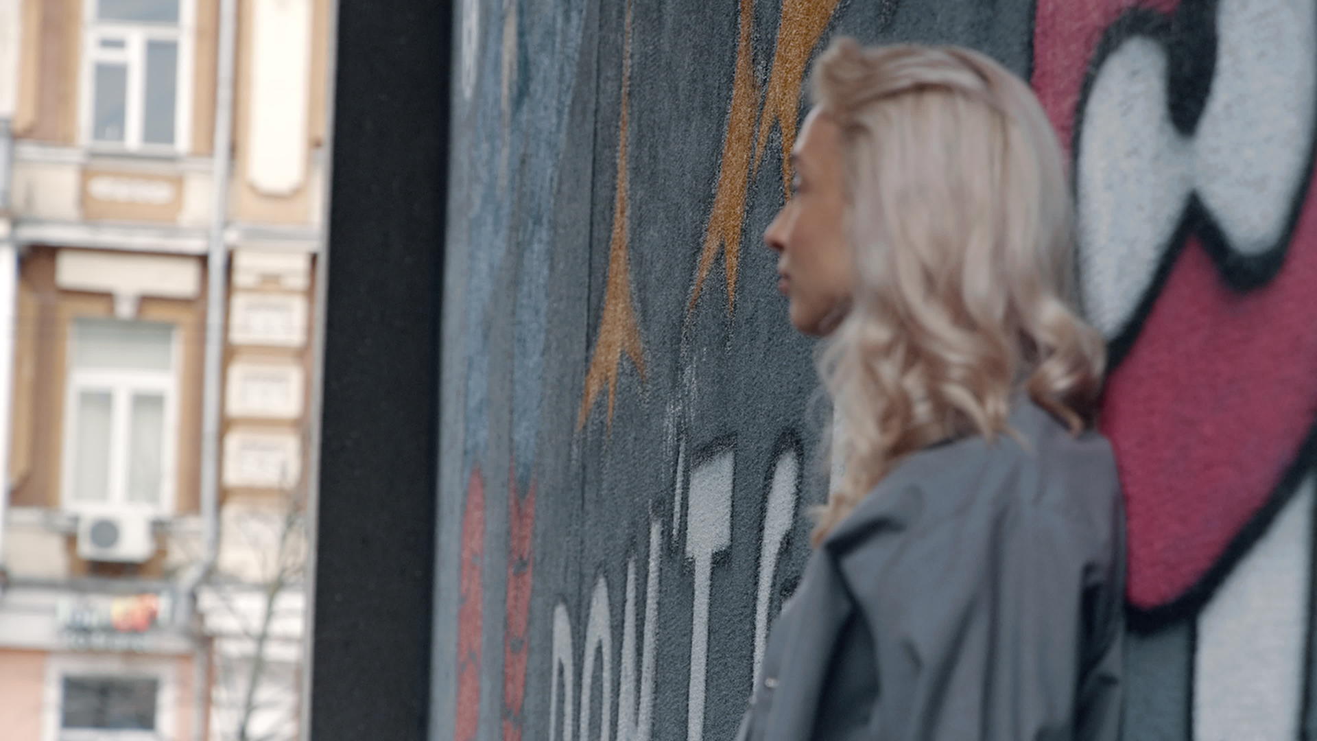 在城市建筑的涂鸦墙附近金发女性可以看到城市景观视频的预览图