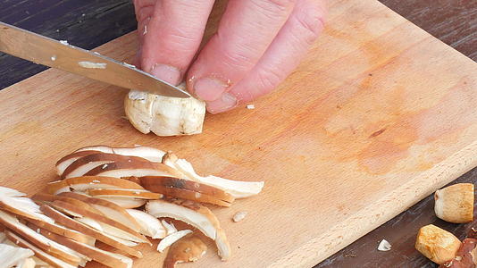 男厨师用刀切新鲜的野生蘑菇用手切蘑菇视频的预览图