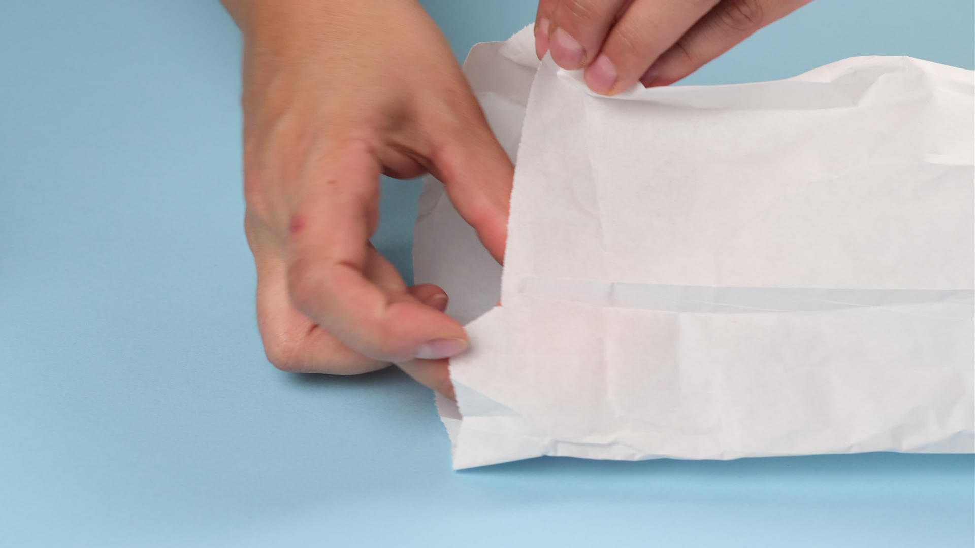 双手折叠成两个多色烤面纱放在一个白色纸袋里视频的预览图