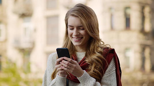 快乐女孩在户外智能手机上发短信视频的预览图