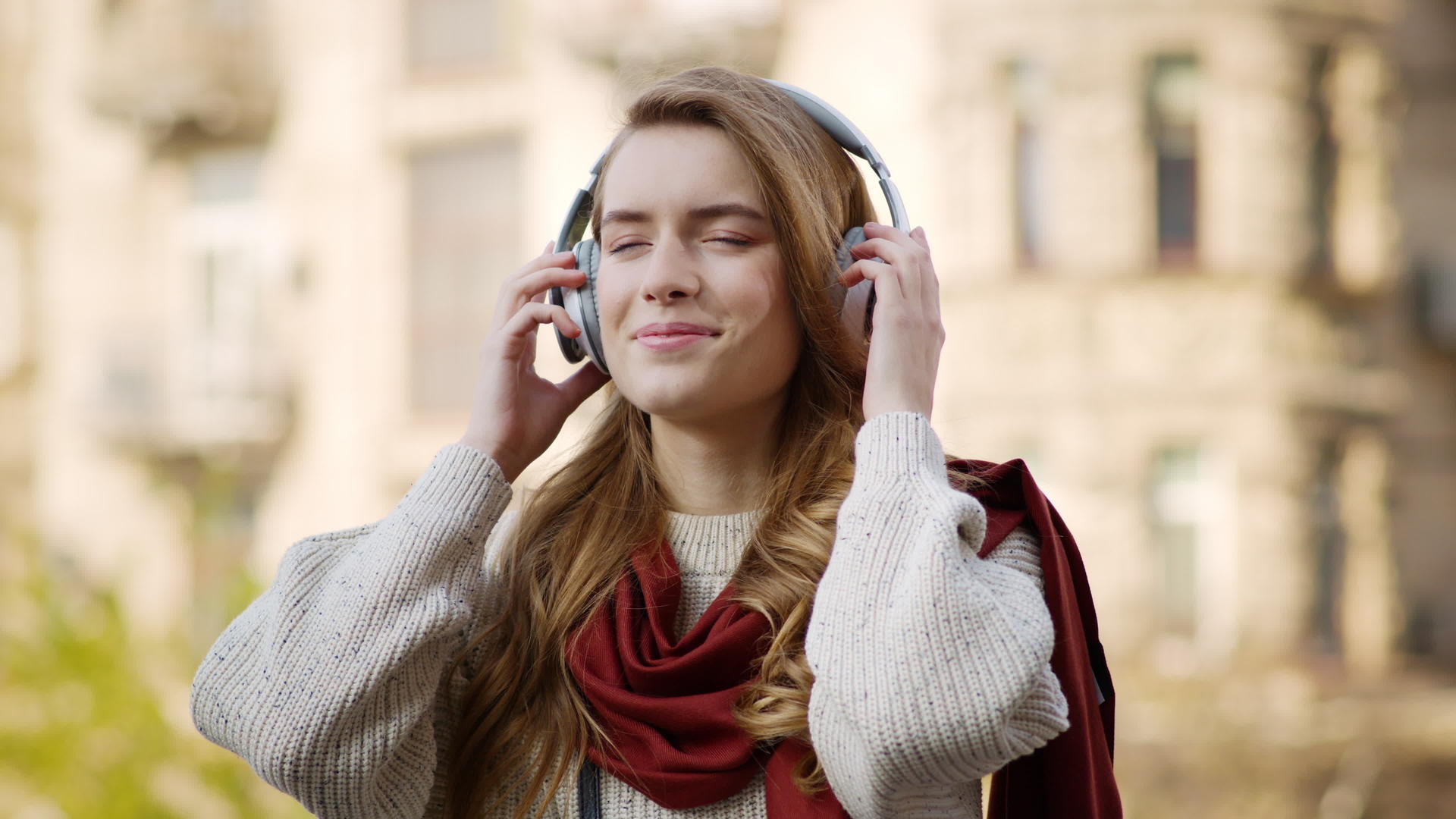 快乐的女人戴着耳机在街上听音乐视频的预览图