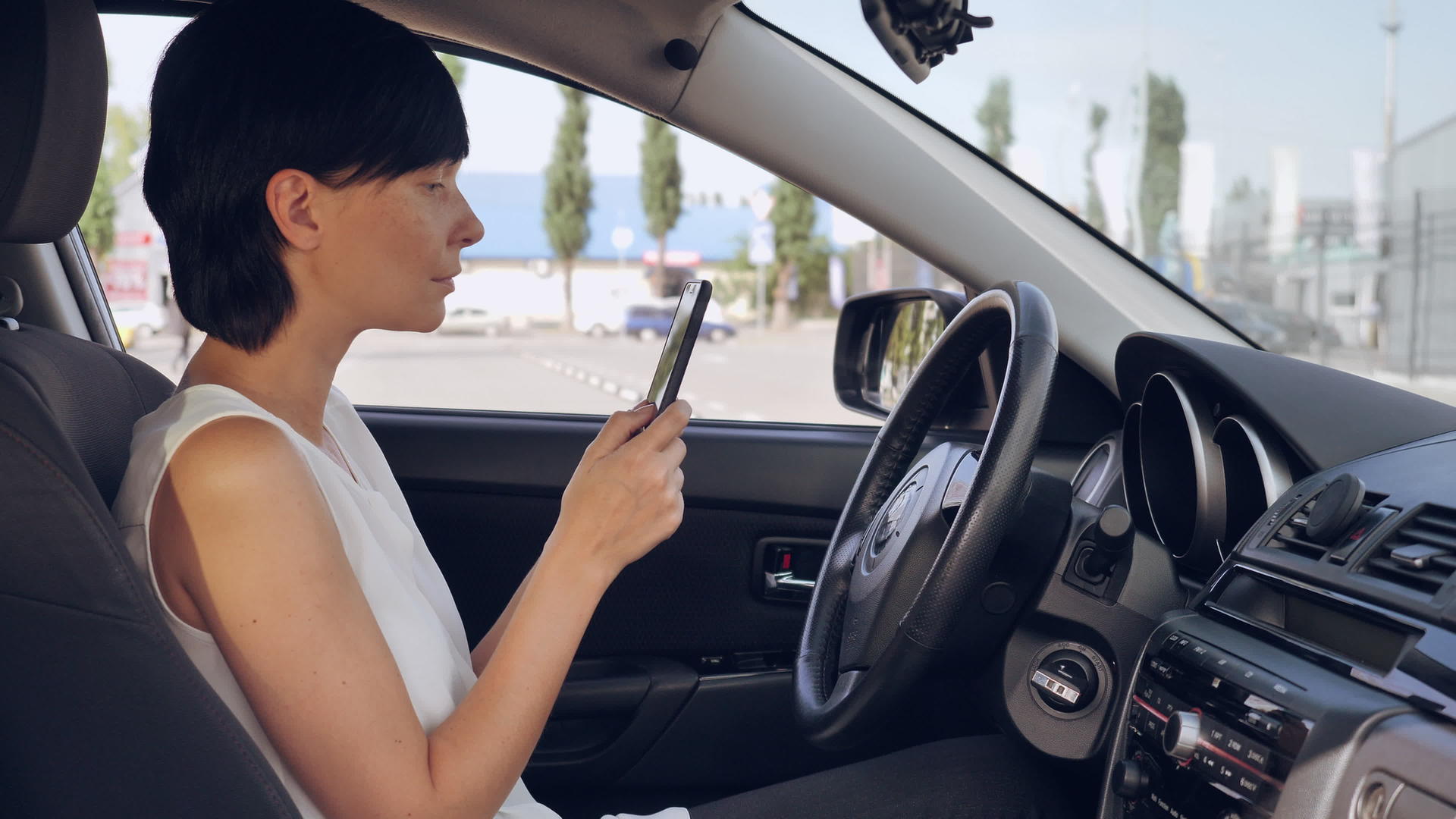 坐在汽车驾驶座上的成年妇女与朋友保持智能电话通信视频的预览图