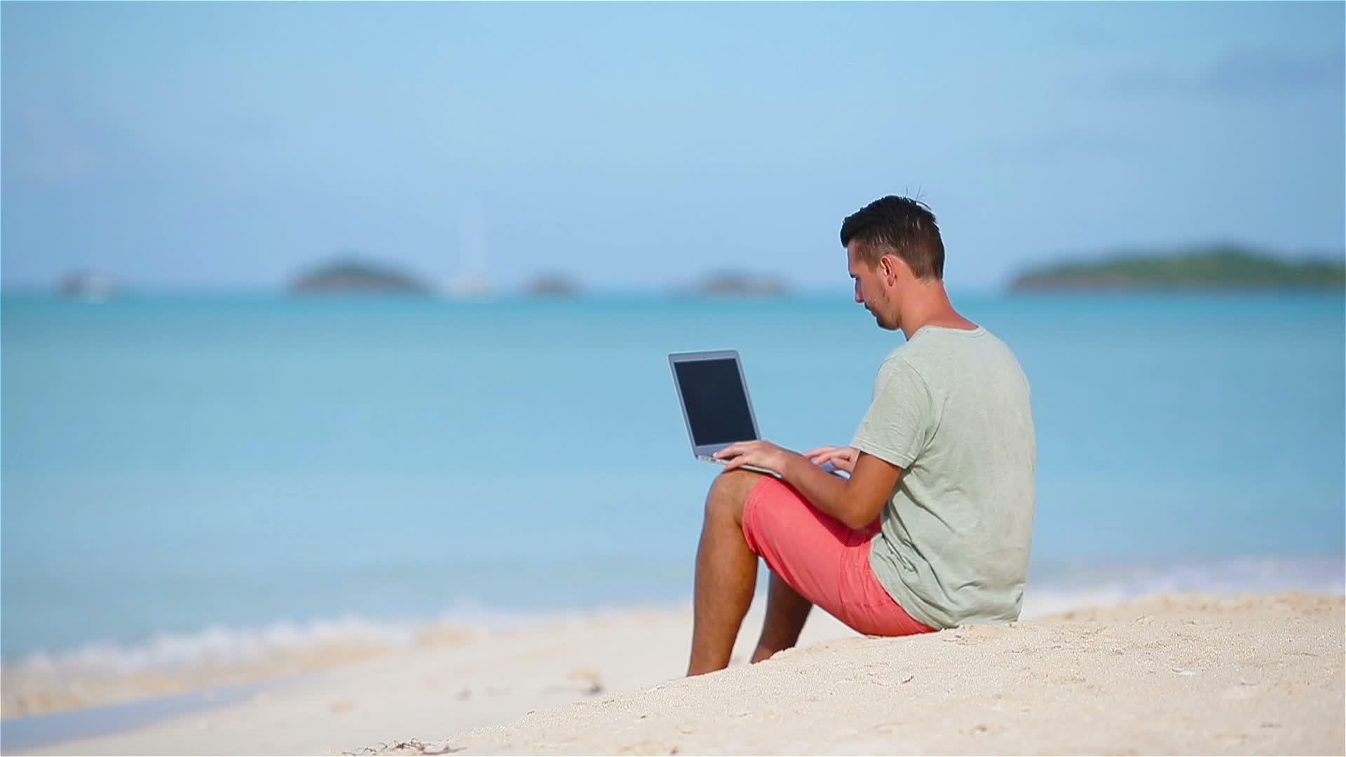 年轻男子在热带加勒比海滩携带笔记本电脑视频的预览图