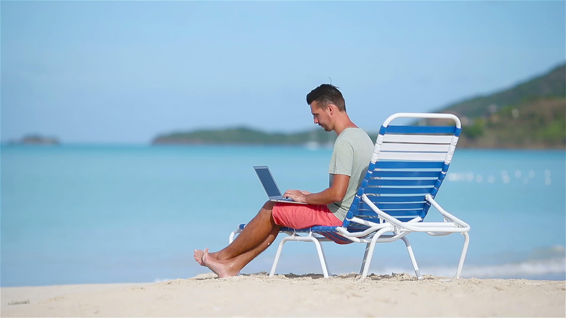 坐在热带加勒比海滩上的年轻男子坐在那里视频的预览图