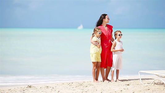 年轻美丽的母亲和可爱的小女儿在热带海滩玩得很开心视频的预览图