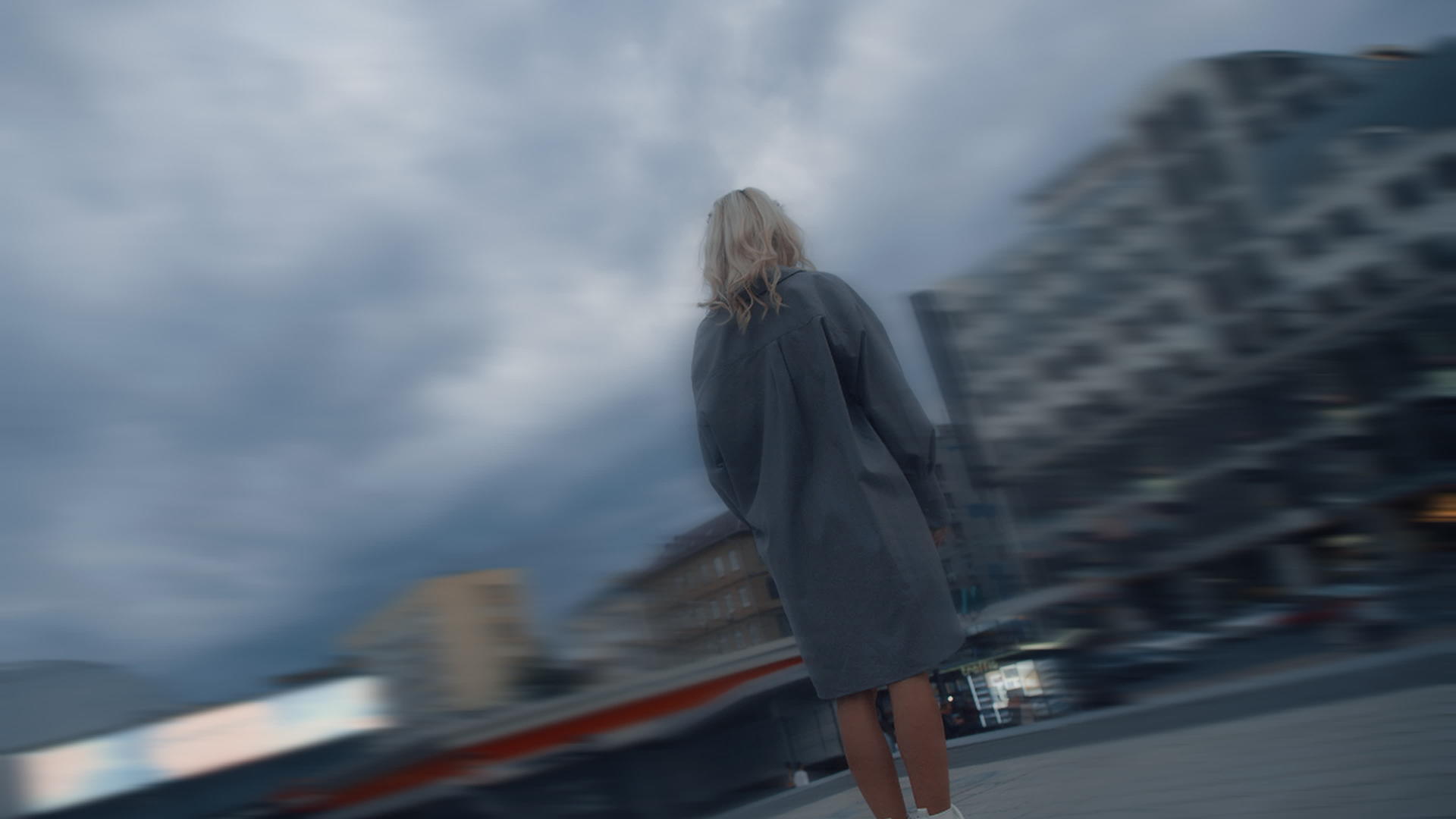 金发碧眼的女人站在多雨的城市里晚上市区的建筑物视频的预览图