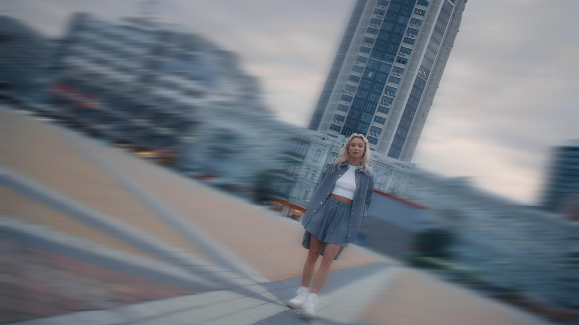年轻女子日落时站在城市现代建筑里视频的预览图