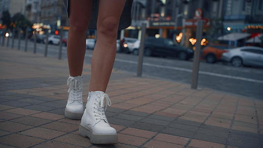 晚上女人的腿在城市附近的公路交通灯附近行走视频的预览图