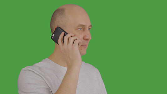 成年男子在绿色背景下通过手机听和说话视频的预览图
