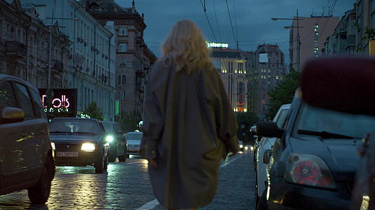 女子晚上离开城市汽车经过黑暗的路灯视频的预览图