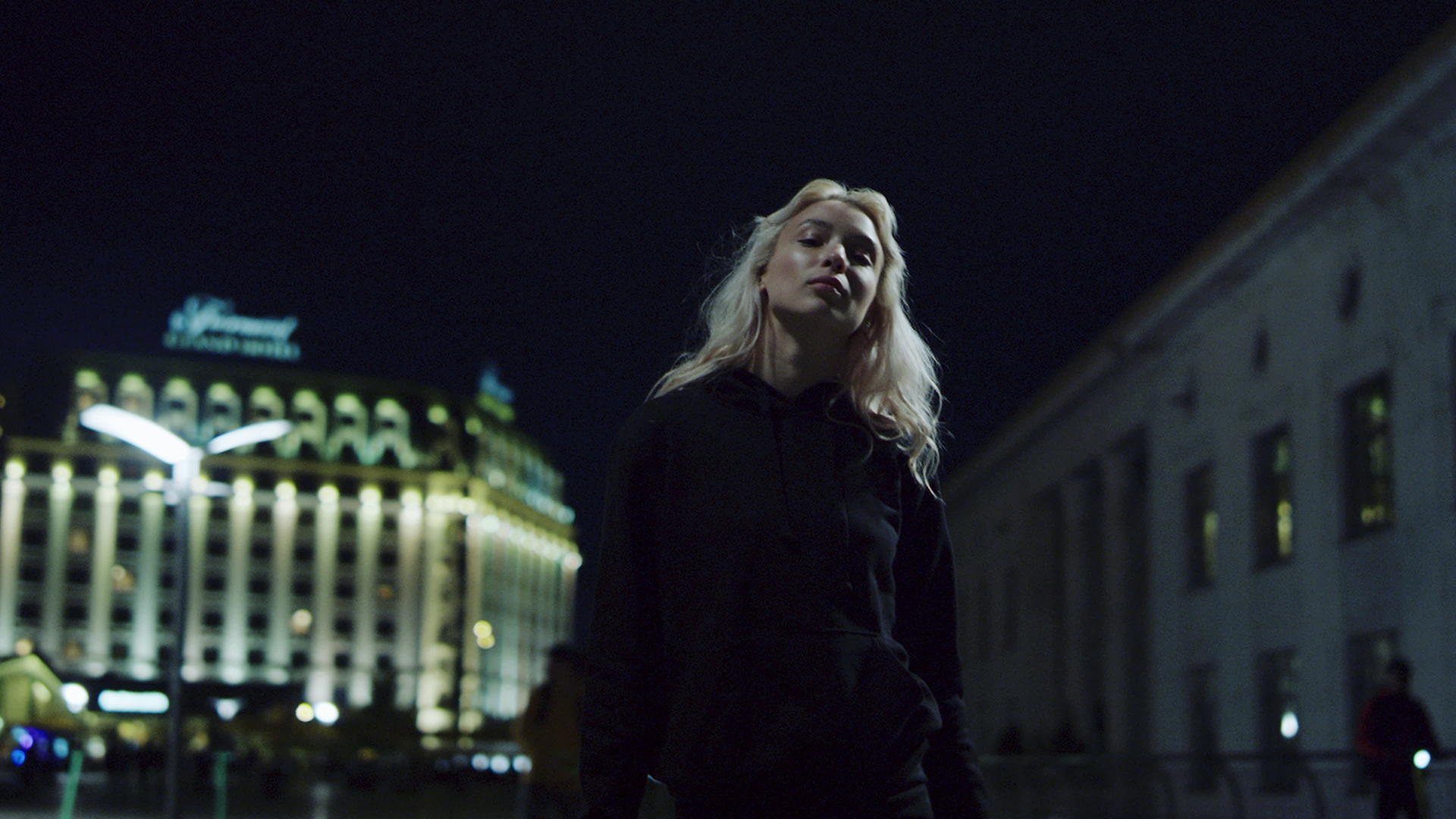 在城市背景下自信的女孩在夜晚的路灯下行走视频的预览图