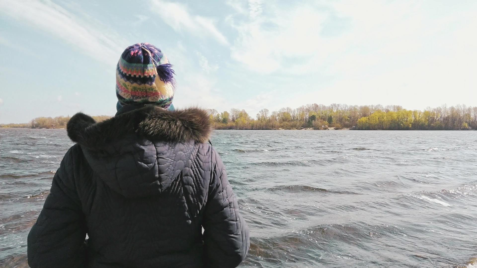 在寒冷的日子里女人看着河水视频的预览图