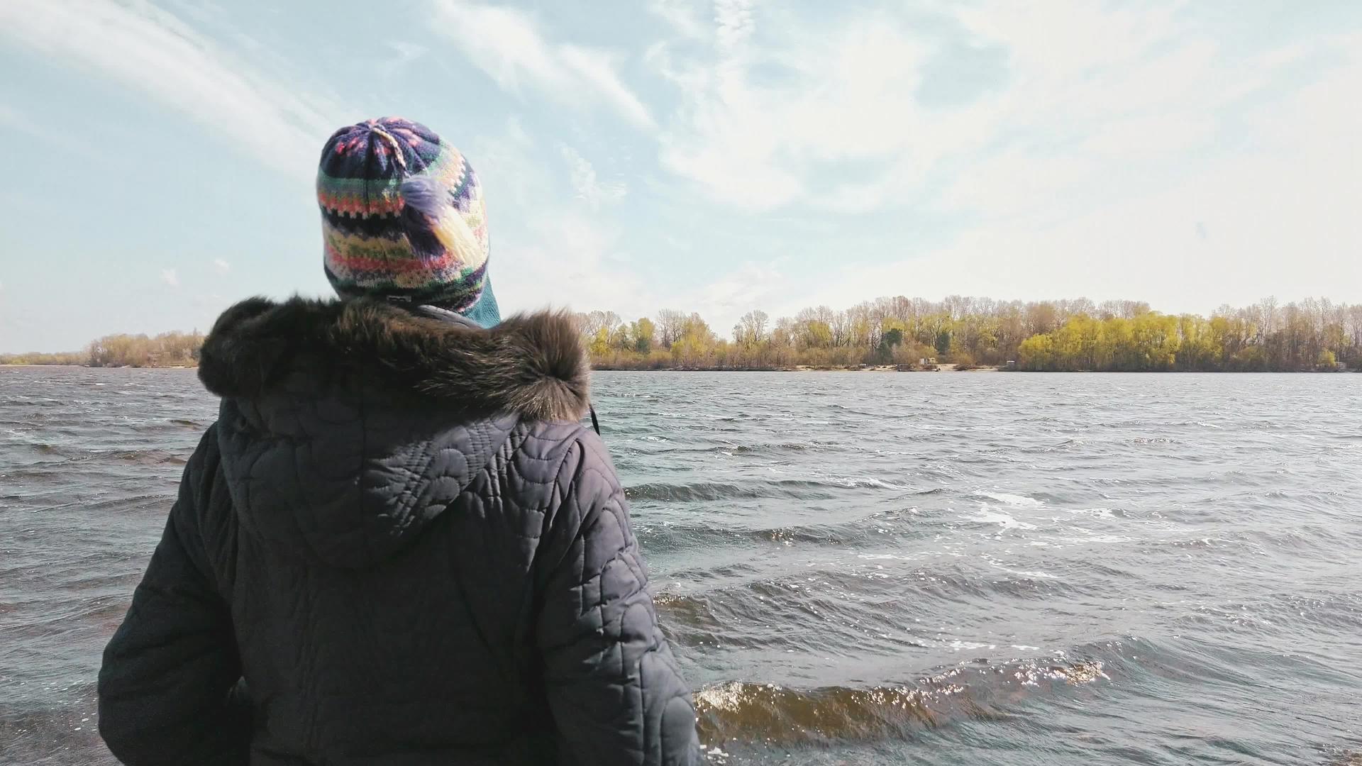 在寒冷的春天女人看着河水视频的预览图