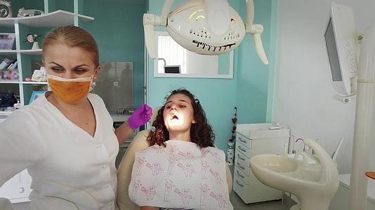 在牙医办公室接受牙科治疗的美容女性患者女孩在看牙医时需要看牙医视频的预览图