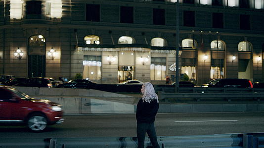 女子站在高速公路上晚上穿着城市服装在市中心视频的预览图