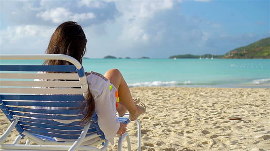 放松和享受暑假的女人躺在沙滩上晒日光浴视频的预览图