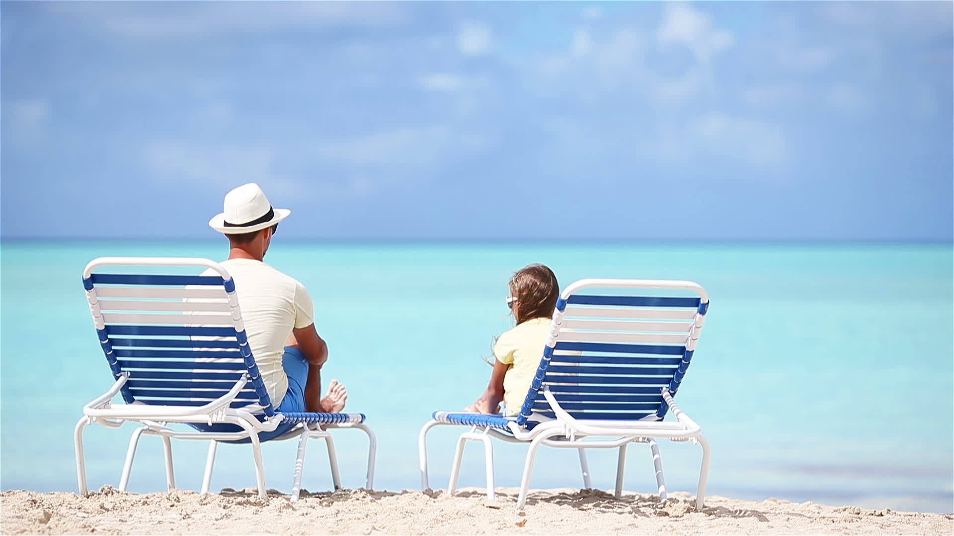 父亲和女儿坐在海滩上视频的预览图