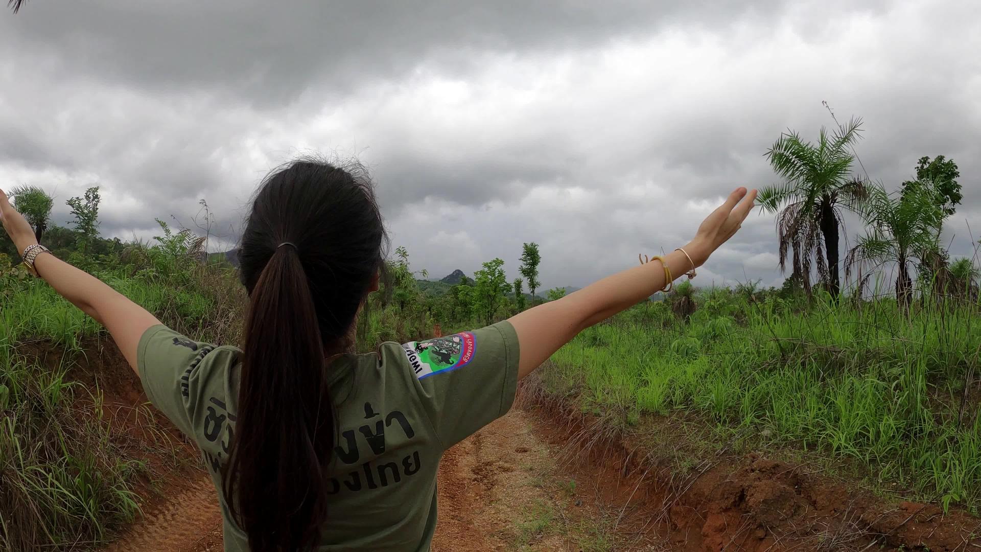 站在泥砾路的田地上年轻女孩举起手视频的预览图