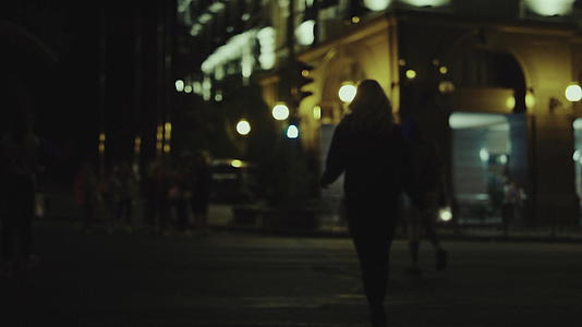 市中心城市灯火通明的人行横道上女性过马路视频的预览图