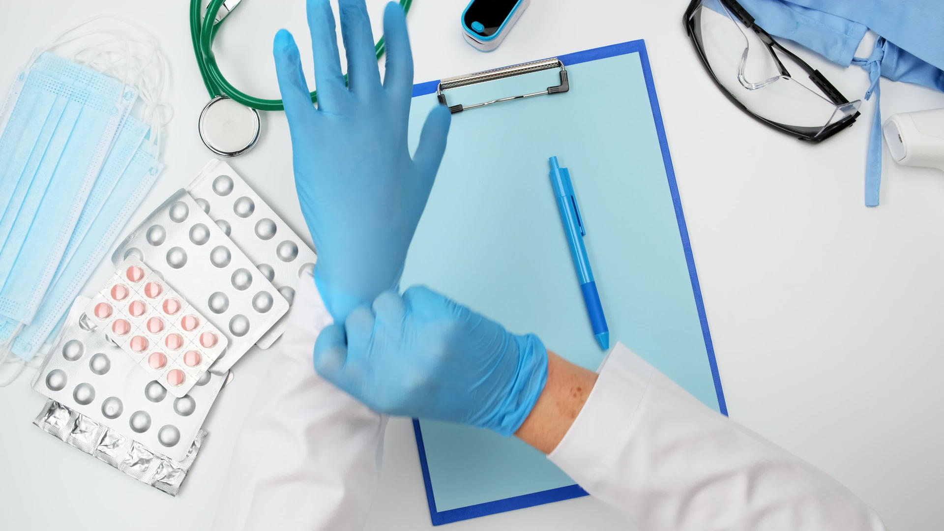 医生穿着白色外套坐在工作台前双手戴着蓝色乳胶手套视频的预览图