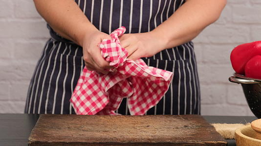 一个穿着蓝色围裙的女人拿着厨房里的红色纺织餐巾纸视频的预览图