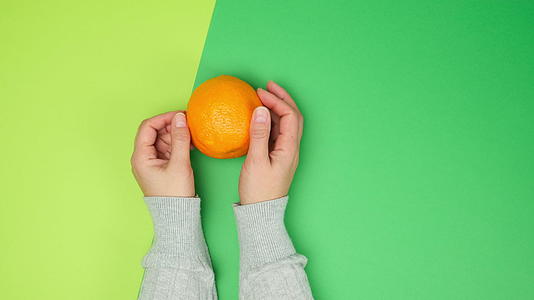 两只母亲的手在绿色背景上干了一整块熟橙子视频的预览图