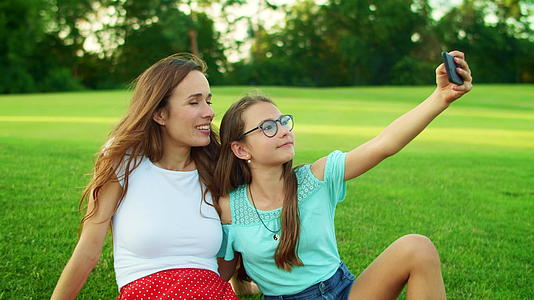 女孩和人在公园里用智能手机自拍视频的预览图