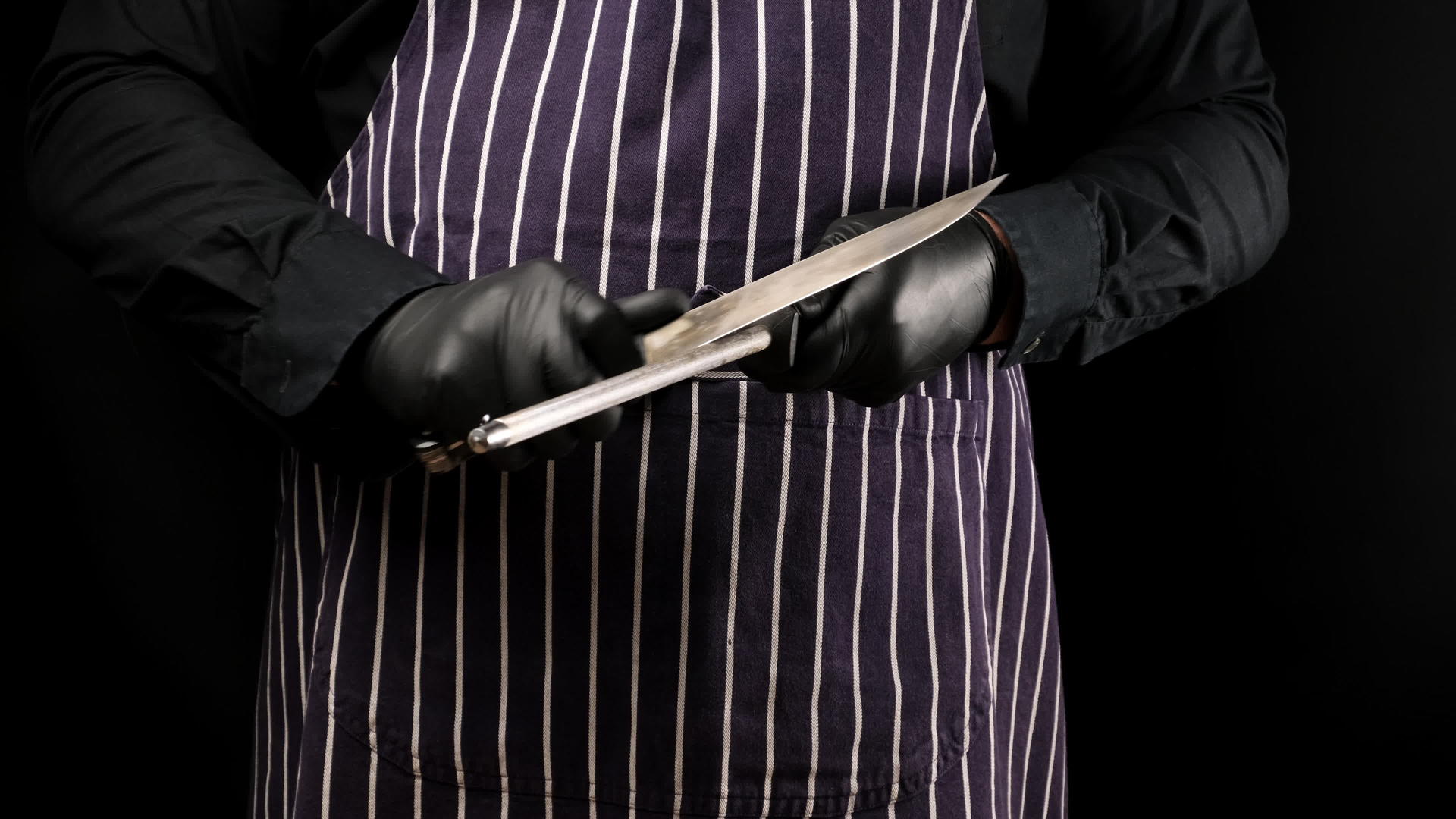 身穿条纹围裙的男子和身穿黑色制服的男子用黑色金属磨刀磨刀视频的预览图