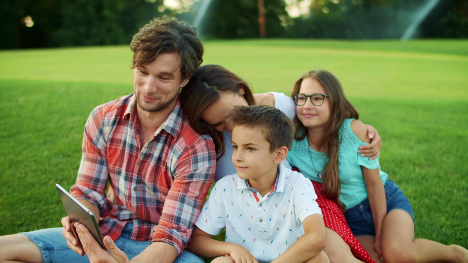 一家人坐在公园的草地上视频的预览图
