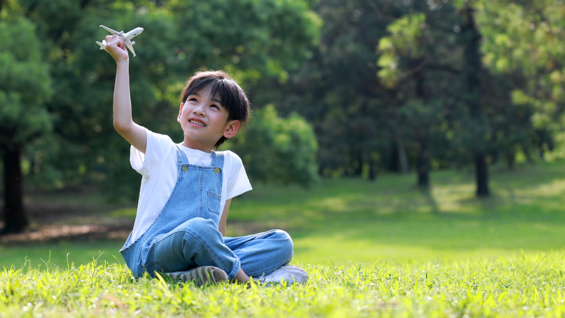 小朋友坐在草地上玩小飞机视频的预览图