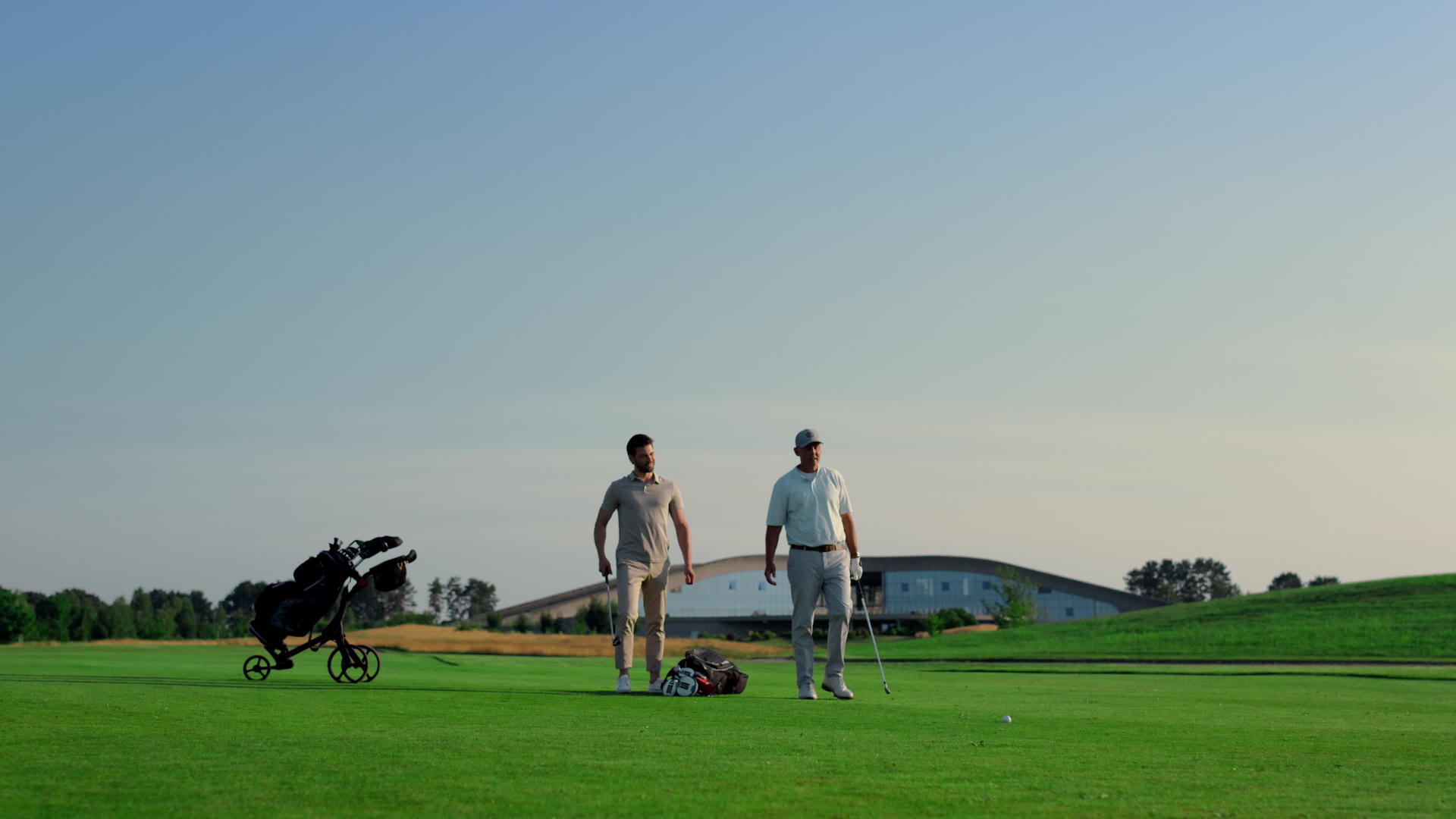 两名高尔夫球手在户外的绿草球场上谈论比赛的准备工作视频的预览图