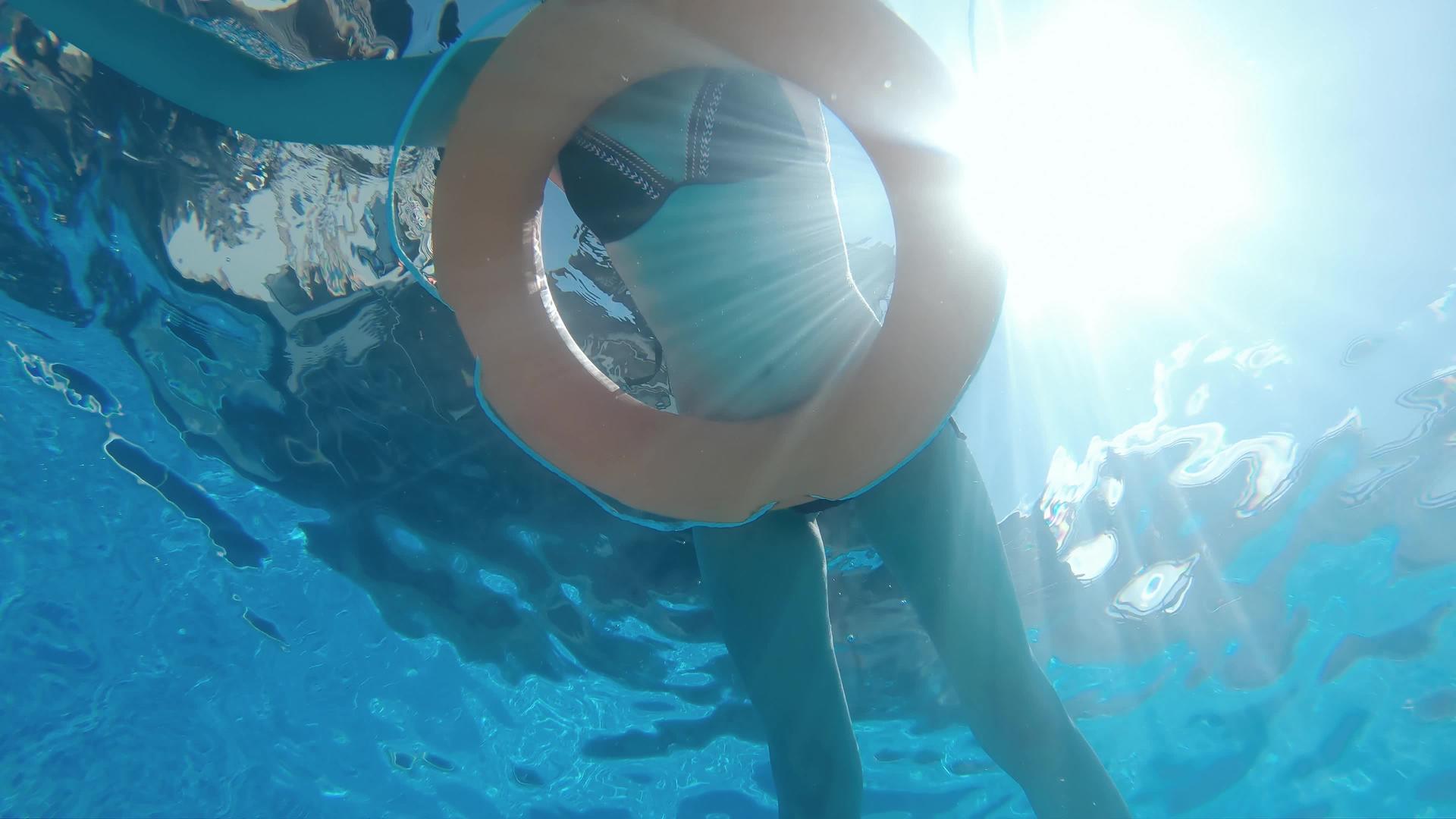 漂亮的女人在游泳池里放松用充气安全环缓慢移动水下风景视频的预览图
