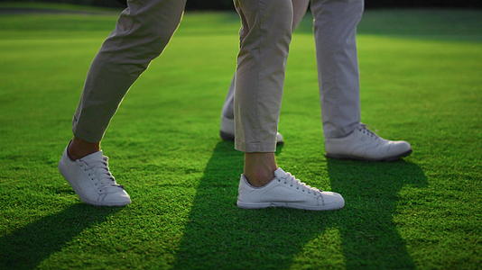 两名高尔夫球手的腿在绿草地上行走视频的预览图