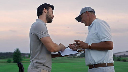 在日落球场上活跃的运动员讨论高尔夫视频的预览图