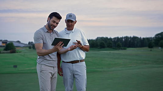 两名高尔夫球手在田野上搜索平板电脑视频的预览图