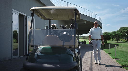 有钱的高尔夫球手走在驾驶推车上视频的预览图