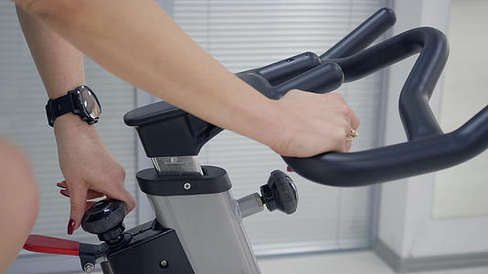 在训练过程中驾驶室自行车调整手柄和手柄栏的健身女视频的预览图