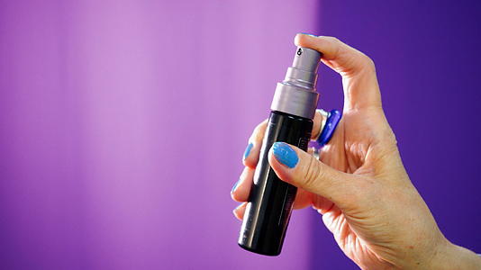 女人用喷雾瓶在紫色背景上喷东西视频的预览图