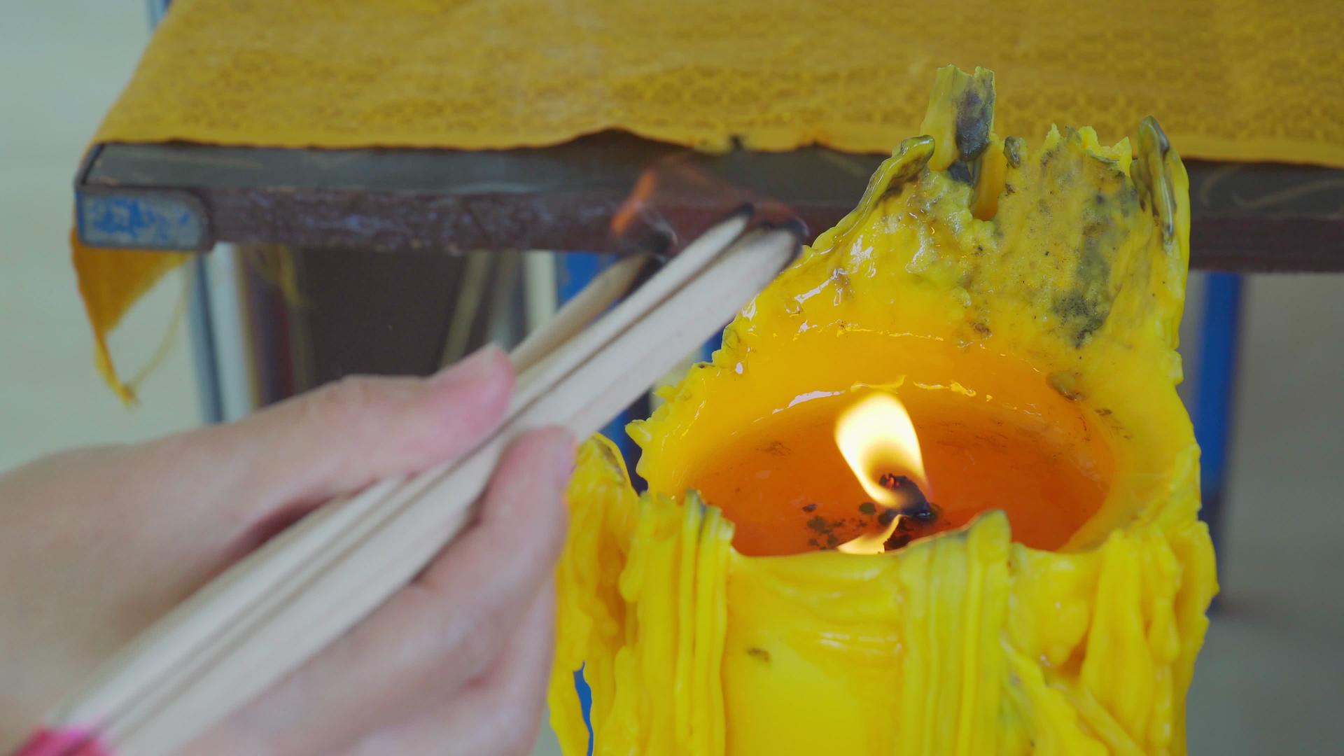 一个女人的手正在从寺庙的一根大蜡烛上烧香视频的预览图