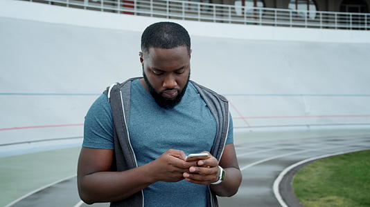 在体育场使用智能手机的运动员在智能手机上发送短信视频的预览图