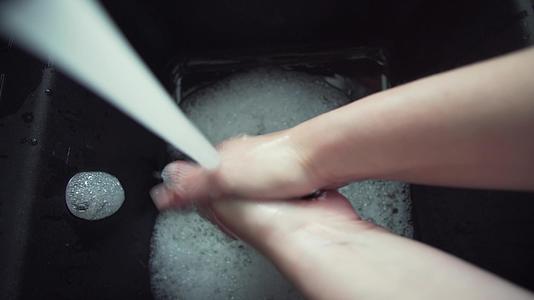 女人在水槽里用肥皂和水洗手 传播到水槽里视频的预览图