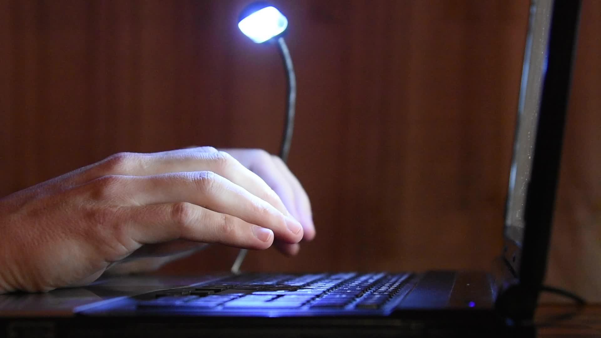 在电脑键盘上的手键上打字从上面的灯台上照亮键盘视频的预览图