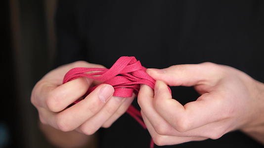 男人解开红色的绳子把手放在模糊的背景上背景是深色4k视频的预览图