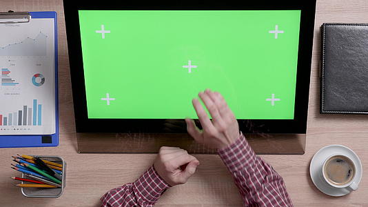 男子显示器上绿色屏幕中心的男子手的顶部视图视频的预览图