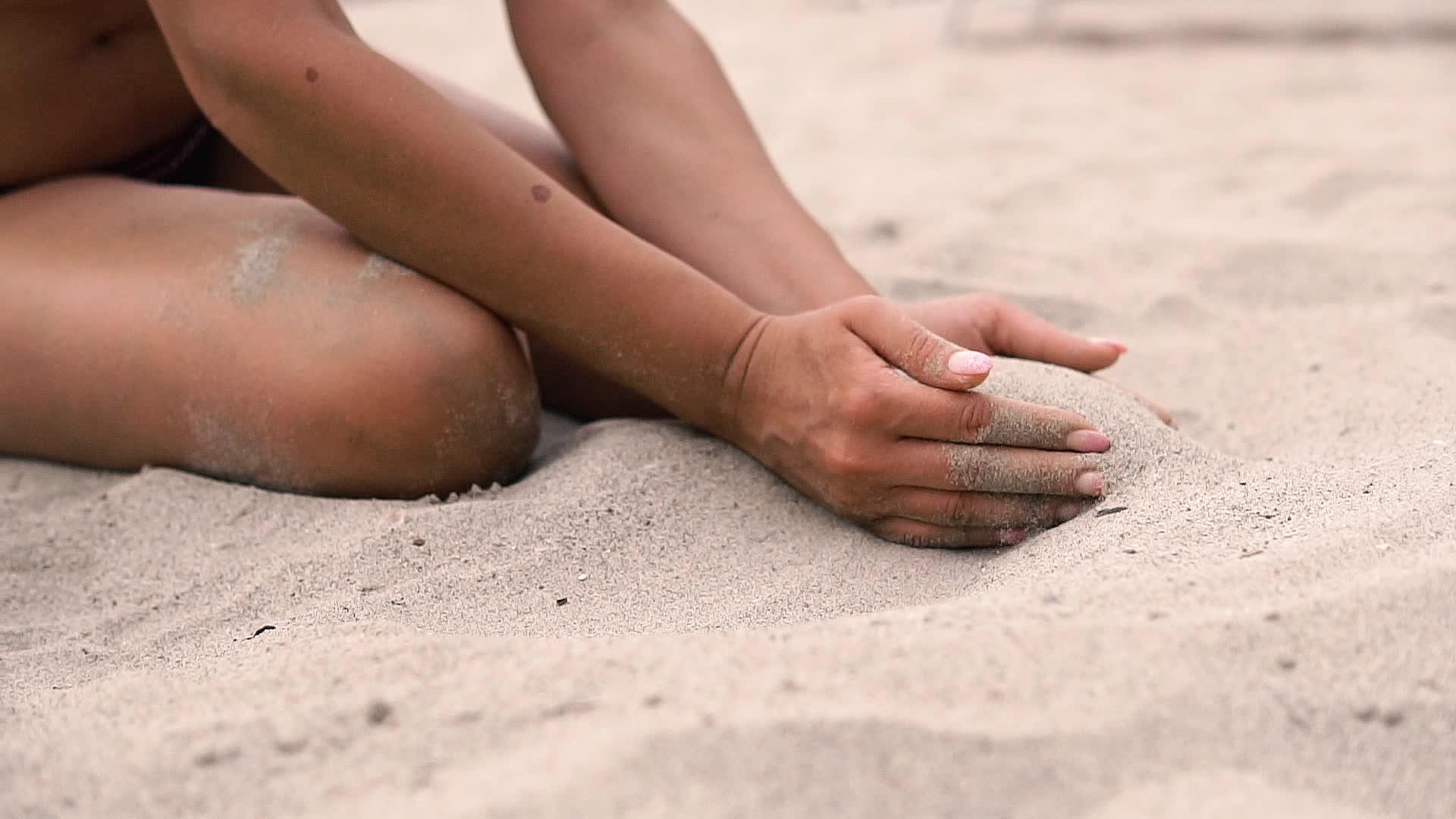 性感的女人坐在沙滩上用手指在沙滩上视频的预览图